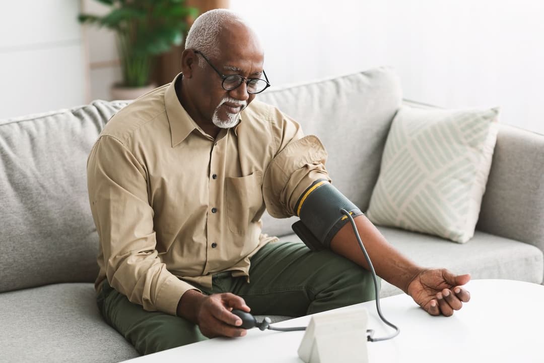 Senior using blood pressure cuff for remote monitoring