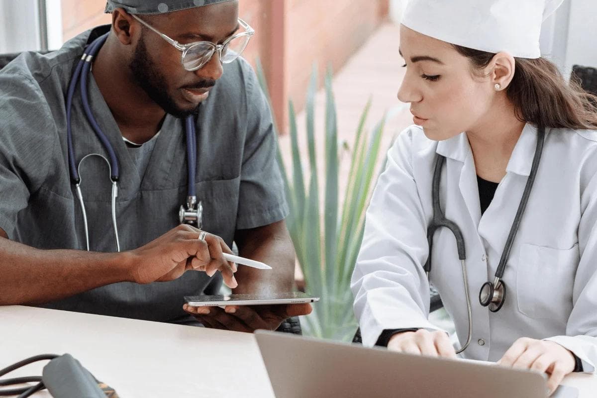Medical professionals review patient data on a tablet, highlighting healthcare teamwork and clinical collaboration.