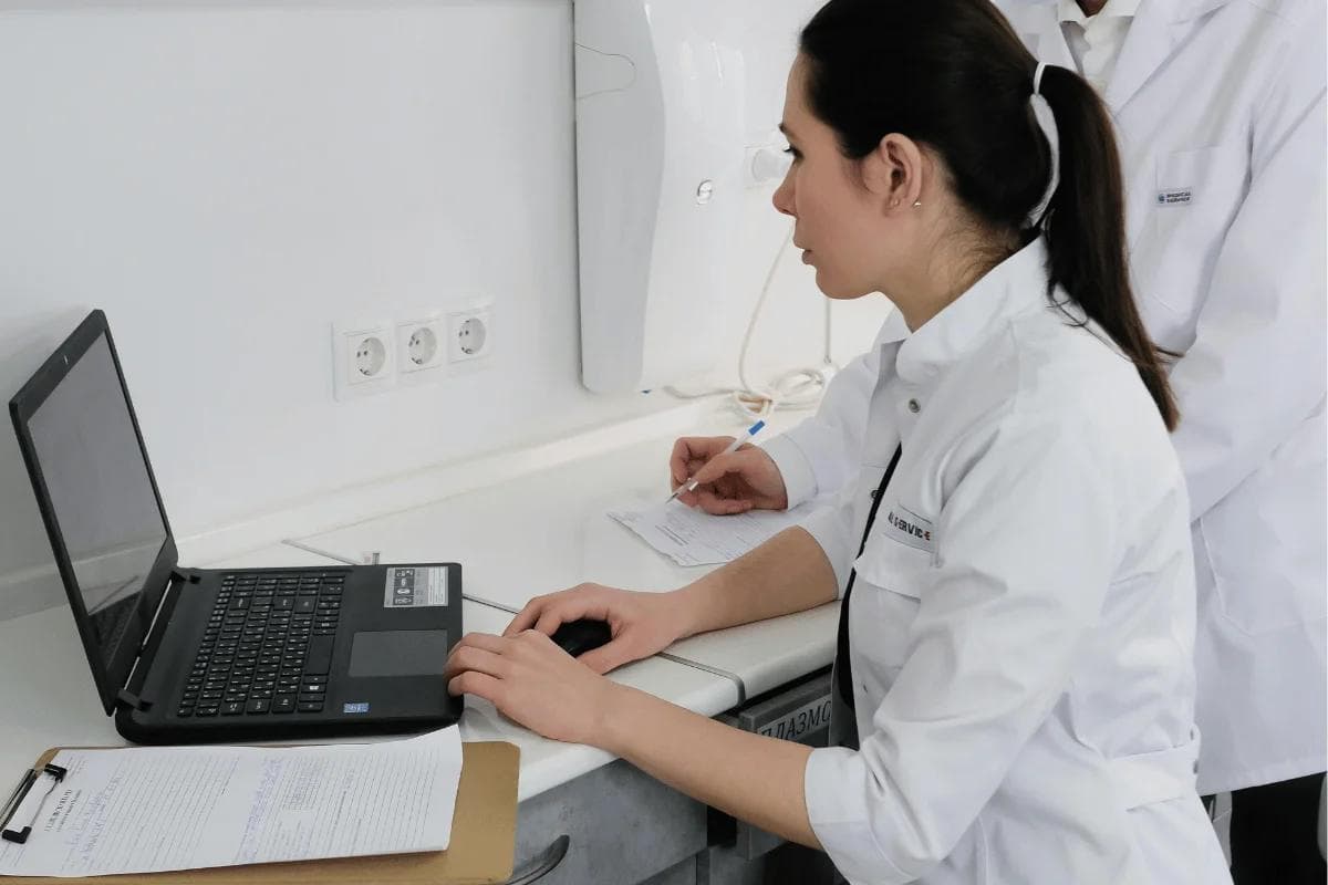 Female doctor working on laptop and taking notes.