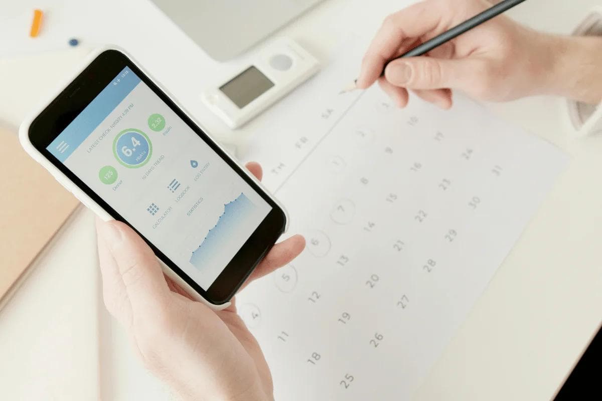 Digital health stats viewed on phone while scheduling on paper.