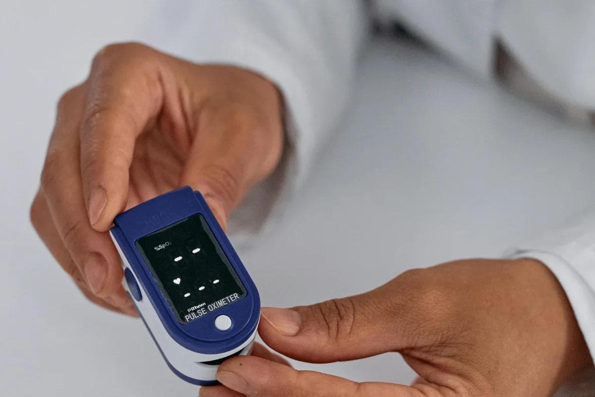 Close-up of person using pulse oximeter to measure oxygen levels.