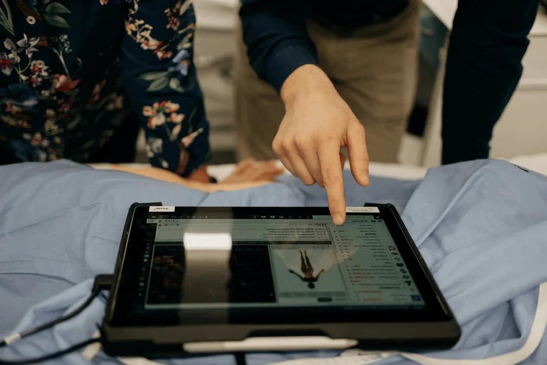 A person points at a medical display on a tablet in a healthcare setting.