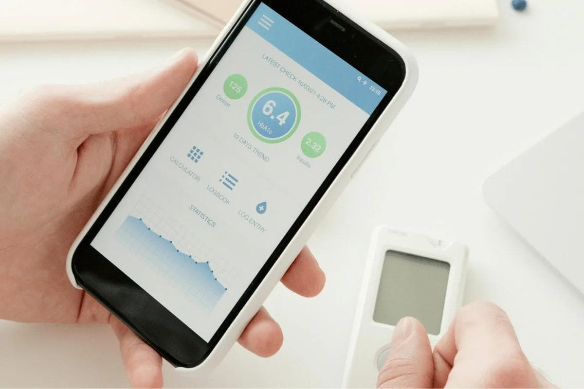 Mobile app displaying blood sugar stats in user's hand.