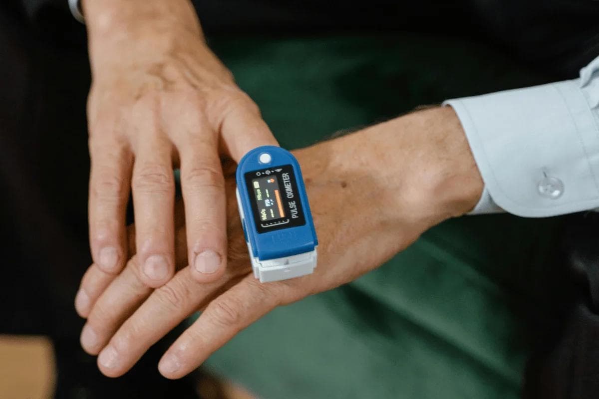 Hand with pulse oximeter measuring oxygen levels.