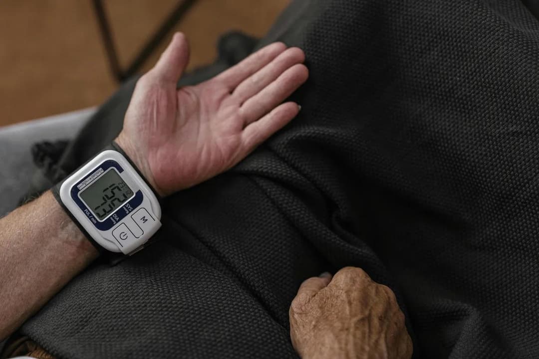 Senior wearing wrist blood pressure monitor while resting.