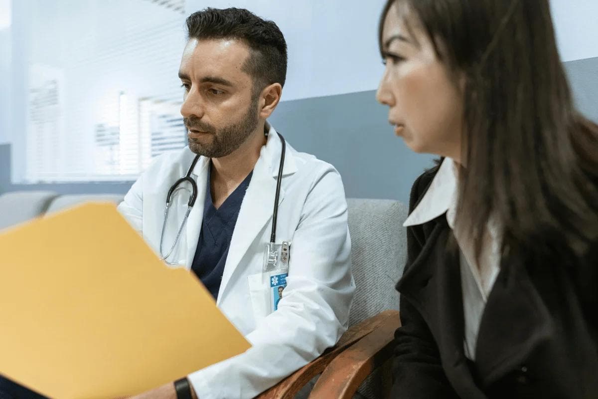 Doctor reviewing patient file and discussing diagnosis during medical consultation.